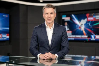Présentateur homme en costume marine derrière un bureau de plateau télévision sur un plateau de news
